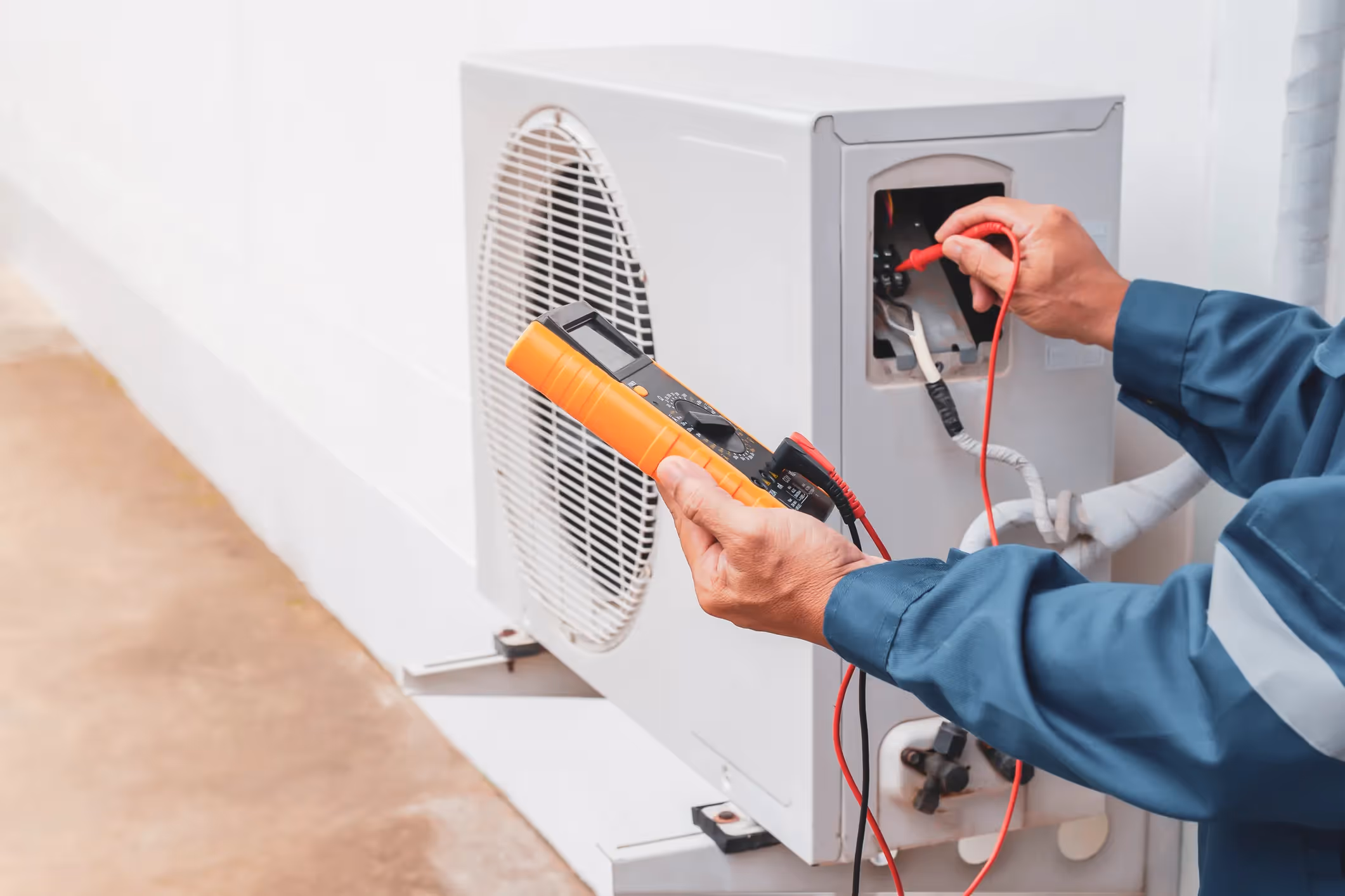 Professional HVAC technician using digital gauges to test the electrical connections and voltage of an indoor air handler Professional HVAC technician using digital gauges to test the electrical connections and voltage of an indoor air handler